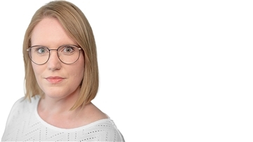 Eine blonde Frau mit dunkler Brille schaut in die Kamera.