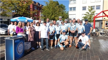 Radsportteam der Betriebssportgemeinschaft der Polizei Hamburg auf dem Theodor-Heuss-Platz neben einem Infostand des "Weißen Ring"