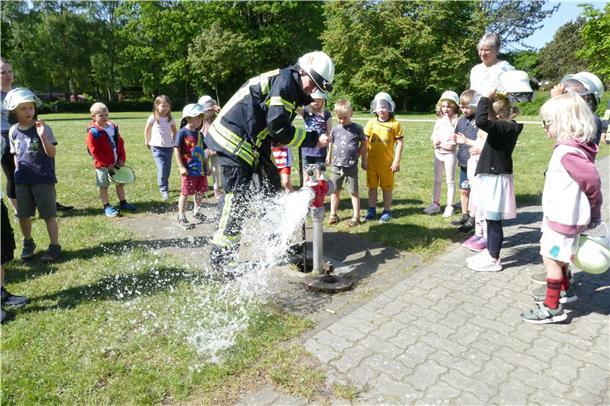 Wilstedter Kita-Kinder lernen vieles über Feuer und Wasser Wasser spritzt aus einem Schlauch. Kinder und Erwachsene schauen zu.