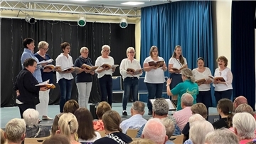 Frauen stehen auf der Bühne und singen ein Chorkonzert.