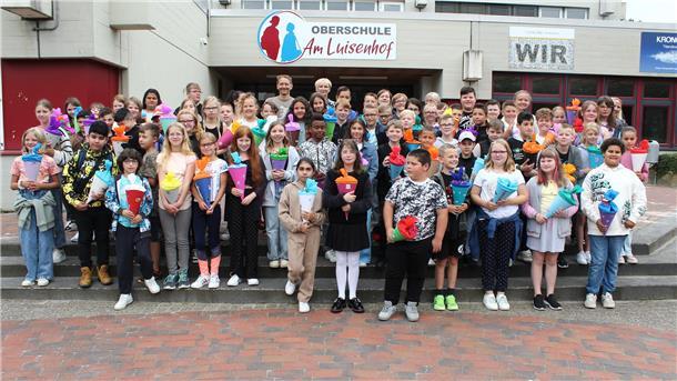 Viele Jungen und Mädchen stehen mit Schultüten vor dem Schulgebäude.