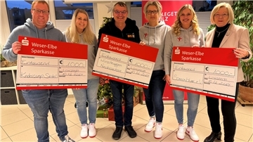 Mehrere Menschen halten drei Spendenschecks in den Händen