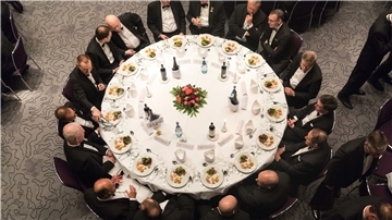 Männer sitzen an einem runden Tisch.
