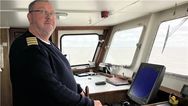 Mit der „Geestemünde“ Containerschiffe aus der Nähe sehen Mann am Steuer eines Schiffes.