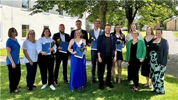 Männer und Frauen haben sich zum Gruppenfoto unter einem Baum aufgestellt