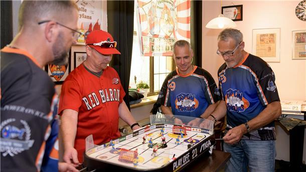 vier Männer in Sportshirts an einem Stiga-Hockey-Tisch