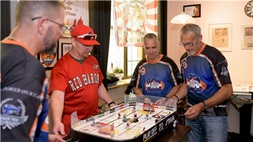 vier Männer in Sportshirts an einem Stiga-Hockey-Tisch