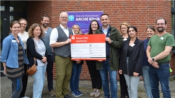 Mitarbeitende der Diakonie Bremerhaven und Vertreter des Edeka Centers stehen gemeinsam vor der ARCHE Klinik und präsentieren einen symbolischen Spendenscheck über 2.239,16 Euro.