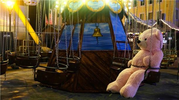 Ein großer Teddybär sitzt in einem Kettenflieger, das auf dem Weihnachtsmarkt in Bremerhaven steht. 