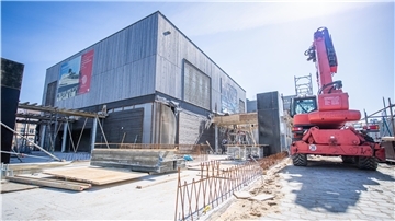 Blick auf die Baustelle für den zweiten Erweiterungsbau des Deutschen Auswandererhauses in Bremerhaven: Die Bauarbeiter sind aktuell mit Betonarbeiten im Erdgeschoss und an der Decke beschäftigt.