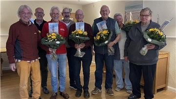 Eine Gruppe von Männern mit Blumensträußen. Die Mitglieder des Vorstands des Butjadinger Bürgerbus-Vereins wurden in ihren Ämtern bestätigt.