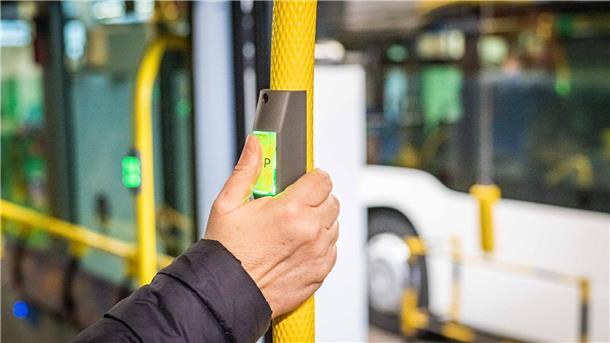 Hand drückt das Stopsignal in einem öffentlichen Bus