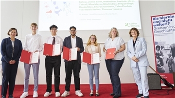 Mehrere Menschen stehen auf einer Bühne und halten Auszeichnungen in der Hand. 