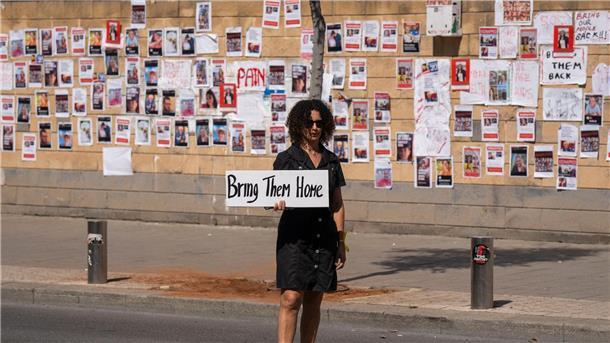 WHO rechnet Freitag mit Grenzöffnung in Rafah „Bringt sie nacht Hause“ steht auf dem Schild dieser Frau, die in Tel Aviv vor einer Wand mit den Fotos von Israelis steht, die von der Hamas im Gazastreifen gefangen gehalten werden.