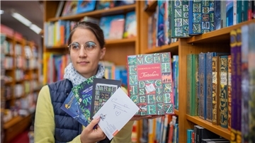 Buchhändlerin Alexandra Köpping präsentiert die Autogrammkarten und ein Buch von Cornelia Funke.