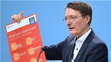 Bundesgesundheitsminister Karl Lauterbach (SPD) hält ein Plakat zum Thema Hitzeschutz hoch.