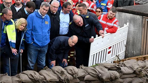 Süddeutschland ächzt unter dem Hochwasser Bundeskanzler Olaf Scholz (1. Reihe, v.r.), Bayerns Innenminister Joachim Herrmann, Ministerpräsident Markus Söder und Bundesinnenministerin Nancy Faeser stehen hinter einer Absperrung aus gefüllten Sandsäcken bei einer Ortsbesichtigung in Reichertshofen.