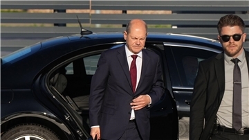 Bundeskanzler Olaf Scholz (l, SPD) kommt zum Start einer zweitägigen Reise auf dem militärischen Teil des Flughafens Berlin Brandenburg BER an und steigt aus einer Limousine.