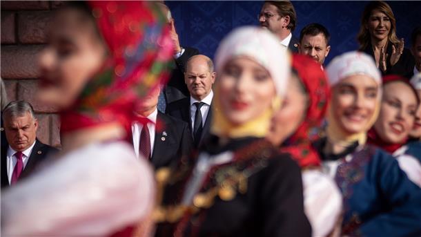 EU will Westbalkanstaaten enger an sich binden Bundeskanzler Olaf Scholz (M) beobachtet eine traditionelle Tanzvorführung beim Familienfoto beim EU-Westbalkan-Gipfel. Links ist Viktor Orban, Ministerpräsident von Ungarn, zu sehen.