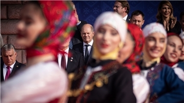 Bundeskanzler Olaf Scholz (M) beobachtet eine traditionelle Tanzvorführung beim Familienfoto beim EU-Westbalkan-Gipfel. Links ist Viktor Orban, Ministerpräsident von Ungarn, zu sehen.