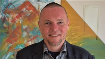 Ein Mann vor einer bunten Wand. Butjadingens Kämmerer Jens Kühne hat überraschend gekündigt.