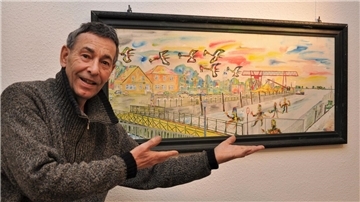 Butjatha vor einem Bild vom Großensieler Hafen. Nach drei Jahrzehnten kehrt der Künstler mit einer Ausstellung zurück nach Nordenham. Die wird am Sonntag um 12 Uhr im Nordenhamer Museum eröffnet.