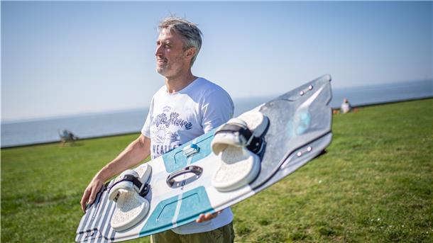 Ein Mann trägt sein Kite-Board.