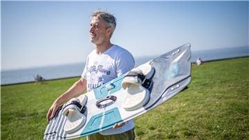 Ein Mann trägt sein Kite-Board.
