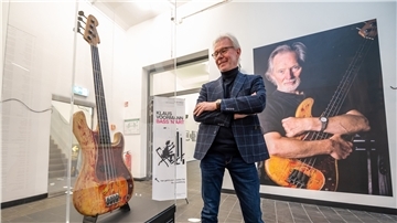Carsten Junge, Leiter der Kunsthalle der Sparkassenstiftung Lüneburg, steht in der Ausstellung neben einer Bassgitarre von Klaus Voormann.