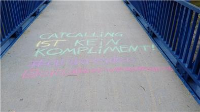 Catcalling im Visier: Rotenburger Polizistin über die unsichtbare Grenze Eine Schrift mit Kreide auf einer Brücke mit blauem Geländer.