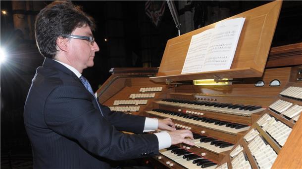 Orgelsommer ElbeWeser: Wandelkonzert und Vivaldi in alten Kirchen Ein Mann im Anzug spielt an einer großen Orgel mit mehreren Manualen und zahlreichen Registerzügen. Vor ihm liegt ein aufgeschlagenes Notenheft.