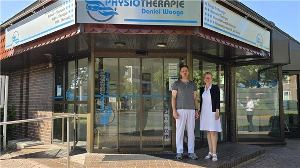 Raiffeisenbank Wesermarsch-Süd baut Geldautomaten in Physiotherapiepraxis ab Christiane Thürlings, Vorstand der Raiffeisenbank, und Physiotherapeut Daniel Wooge stehen vor dem Praxisgebäude.