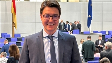 Ein Mann mit Brille und im Anzug steht im Plenarsaal des Bundestages in Berlin.