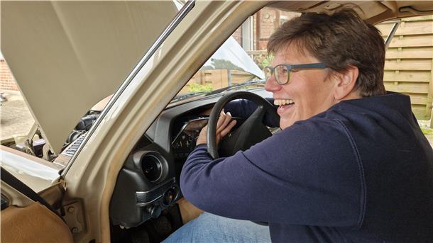 Eine Frau bastelt an ihrem Oldtimer.