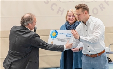 Detlef Zeidler (l.) überreicht das Zertifikat „sportfreundliche Schule“ an Sportlehrer Henry Bentin. Schulleiterin Maike Agit findet‘s gut.