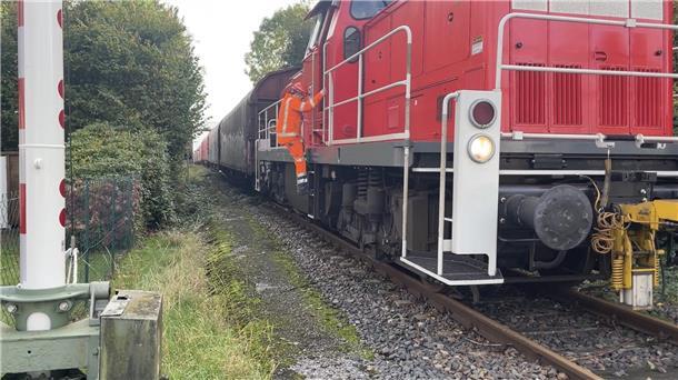 Ein Mann in Sicherheitskleidung steigt aus einem haltenden Cargo-Zug.