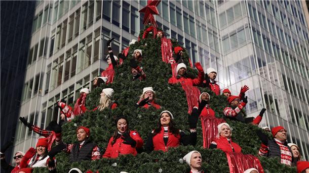 Darsteller auf dem Macy’s Singing Christmas Tree-Wagen winken den Zuschauern während der Macy’s Thanksgiving Day Parade zu.