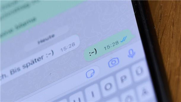 Ein Smiley ist in einem Chat auf einem Handydisplay zu sehen.