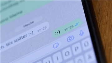 Ein Smiley ist in einem Chat auf einem Handydisplay zu sehen.
