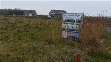 Wiese mit Schild zur Bauankündigung