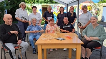 Bild von Seniorinnen und Senioren sowie Mitarbeiterinnen des Malteser Hilfsdienstes im Hof des Mehrgenerationenhauses in Nordenham.