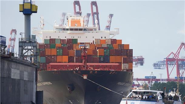 Hapag-Lloyd: trotz Einbrüchen zweitbestes Ergebnis Das Containerschiff „Prague Express“ der Reederei Hapag-Lloyd wird von Schleppern an einen Containerterminal im Hafen gezogen.
