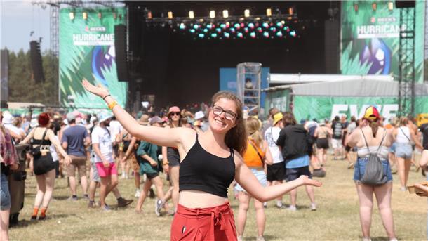 Dreck, Schweiß und Glitzer gehören auf dem Hurricane dazu Im Hintergrund ist eine Bühne des Hurricane-Festivals zu sehen. Im Vordergrund ein Mädchen.