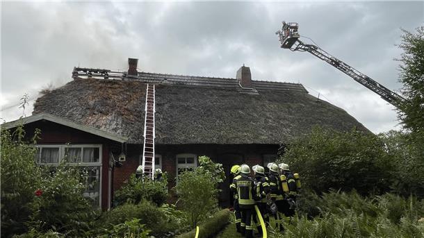 Das Feuer ist von der Gartenlaube auf das Wohnhaus übergegangen. Die Feuerwehr kämpft dagegen an, dass die Flammen auch das Haus zerstören.