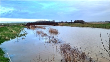 Das Foto zeigt den Grauwallkanal in Höhe Weddewarden zum Jahreswechsel, wie er fast über die Ufer tritt und bereits weite Teile der Wiesen und Weiden unter Wasser gesetzt hat.