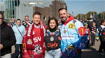 Drei Menschen in Eishockey-Trikots. 