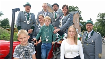 Die Majestäten 2024 des Schützenvereins Driftsethe sitzen auf oder stehen neben einem Traktor.