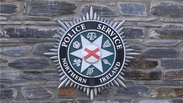 Mann in Nordirland an Zaun genagelt Das Logo des Police Service of Northern Ireland.