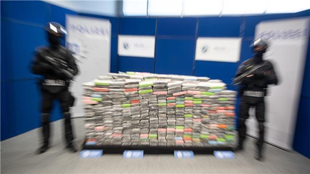 Zwei schwer bewaffnete Polizisten neben hunderte von Kokain-Paketen.