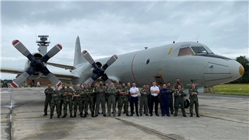 Mehrere Soldaten posieren vor einem Flugzeug.